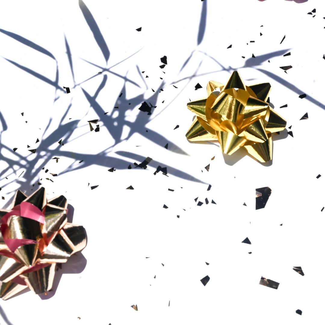 Golden and pink gift bows on a white background with decorative shadows and reflections.